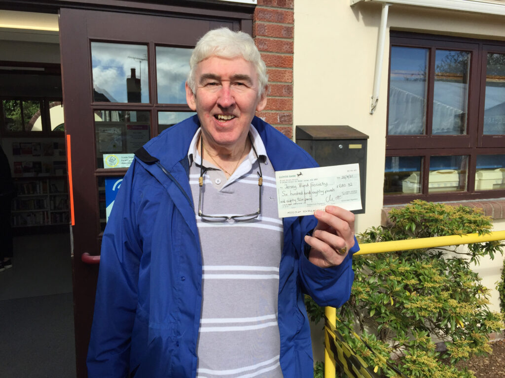 Image of Malcolm outside Westlea Centre holding a cheque with the value of funds raised