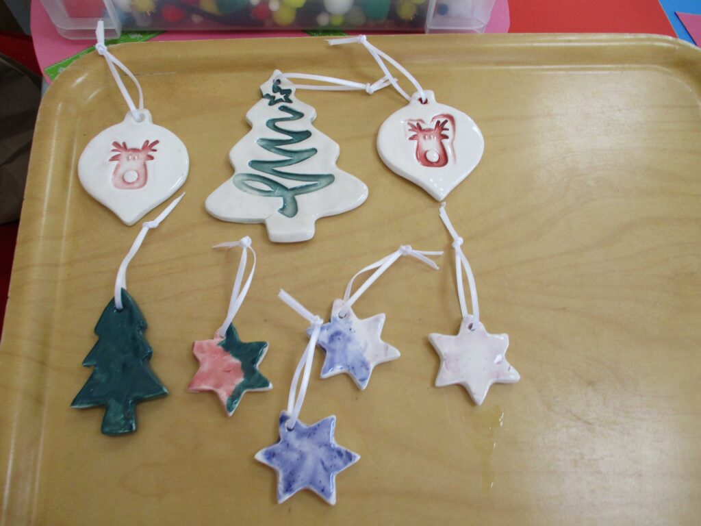 Photo of a collection of completed ceramic Christmas Tree decorations displayed on a table]