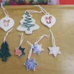 Photo of a collection of completed ceramic Christmas Tree decorations displayed on a table]