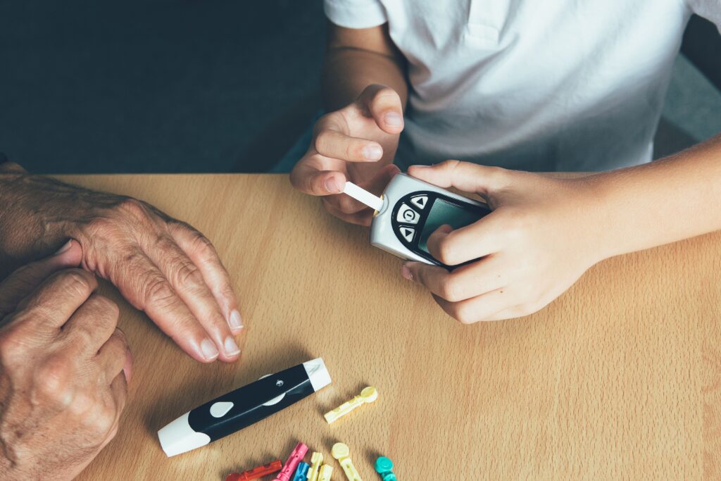 image of a elderly persons hand with a child's hand holding a sugar level device