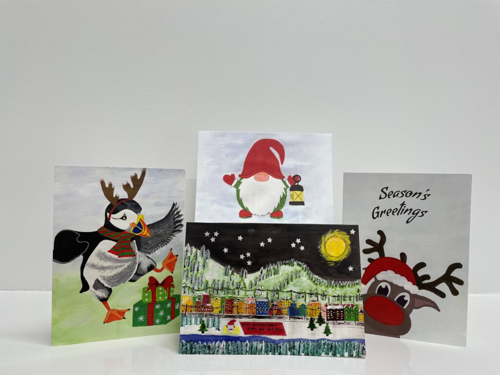 Image shows 4 different Christmas cards. The first card has a drawing of a penguin standing next to gifts, wearing reindeer antlers and a scarf. The second card is a drawing of Gnome carrying a lantern. The third card is a drawing of a city under the nights sky, with Santa Claus standing in front wishing all a Merry Christmas and a Happy New Year. The last card is of a reindeer with a big red nose wearing a red Christmas hat, with the words 'seasons greetings' written above